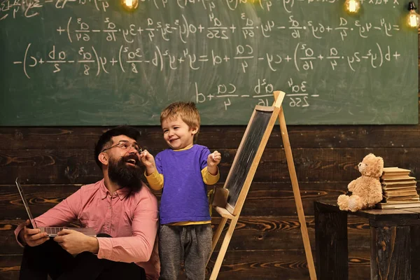 Educación alternativa. Papá y el niño se divierten mientras aprenden nuevas habilidades. Profesor sonriente y colegial sorprendido en el aula. Niño feliz sosteniendo pedazos de tiza en sus manos — Foto de Stock