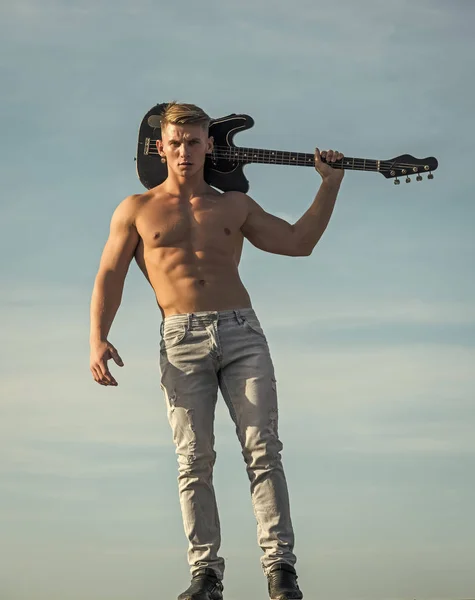 Música, performance, entretenimiento. Guitarrista atleta con paquete de seis, ab en jeans al aire libre —  Fotos de Stock