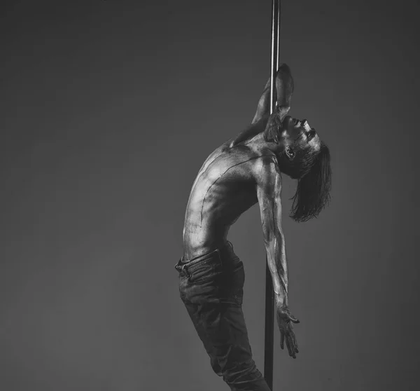 Performance concept. Artistic guy hanging on metallis pole.