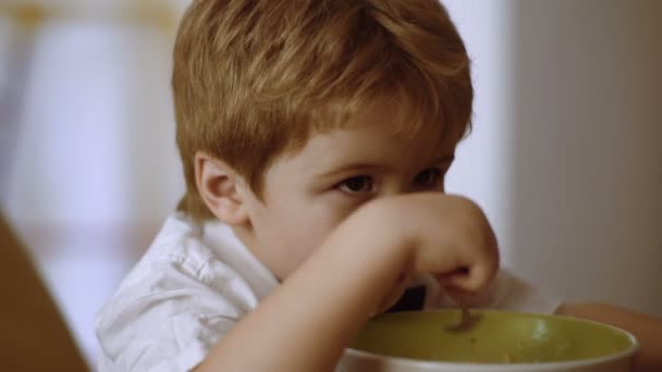 蹒跚学步的男孩用一勺粥喂养自己. — 图库视频影像