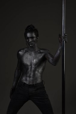 Pilon üzerinde dans gümüş gövde sanat kaslı adam. Metal yüzey ile seksi maço. Pole dans spor. Güçlü dansçı kutup. Özgürlük. Kendine güvenen sporcu. Atletik adam olun akrobatik öğeleri pilon üzerinde