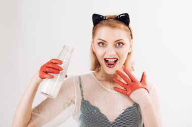 Güzel model kırmızı lateks eldiven portresi kedi kostüm şişeden içme sütü.