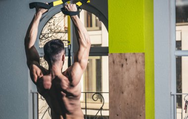 Sporcu, atlet, kas maço mu egzersiz trx döngüler ile arka plan üstünde pencere. Spor ve spor salonu konsept. Adam çıplak gövde ve geri içinde jimnastik salonu kas eğitim, trx, arka görüş zevk