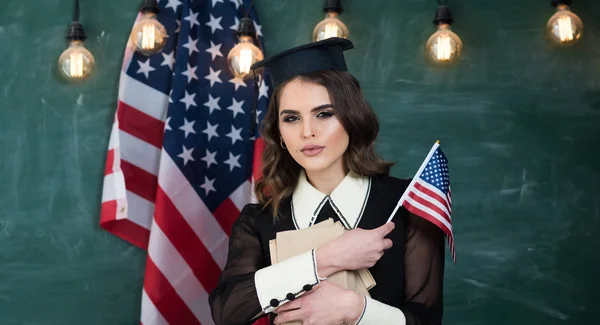 Estudiante con bandera de EE.UU. Concepto de educación y personas: estudiantes sonrientes con bolsos y carpetas mirándose unos a otros sobre el fondo de la bandera estadounidense —  Fotos de Stock