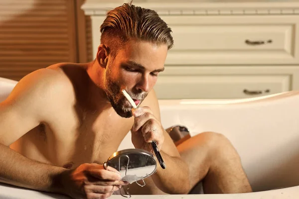 O homem está a barbear-se na casa de banho. Homem Skincare com sabão de barbear na pele do rosto e navalha — Fotografia de Stock