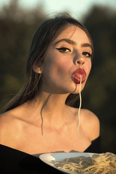 Belleza chica modelo de moda. Mirada de moda. Hambre, apetito, receta. Chef mujer con labios rojos comer pasta. Macarrones italianos o espaguetis para la cena, cocinar. Mujer comiendo pasta como catador o crítico de restaurante — Foto de Stock