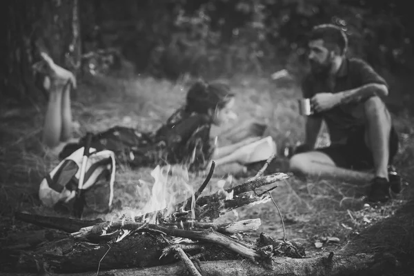 Relações entre mulheres e homens na natureza. Chama de lenha na fogueira queimadura e casal borrado — Fotografia de Stock