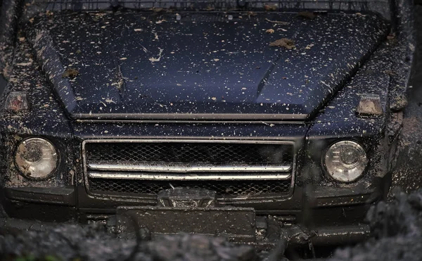 Corsa su auto fuoristrada. Luci e cofano ricoperti di fango. Parte della macchina bloccata — Foto Stock