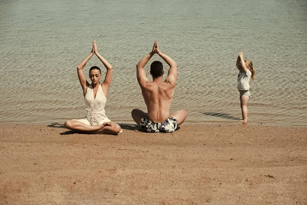 family sport. child, man and woman meditating, yoga pose, famile