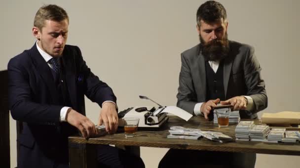 Dois homens contam lucros sentados à mesa e fumam charutos. Empresários são lucros divididos . — Vídeo de Stock