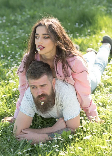 Tempo despreocupado juntos. Casal apaixonado no sol ao ar livre. Mulher deitada sobre um homem com flores na boca. Casal relaxar na grama verde. Desfrute de férias de verão — Fotografia de Stock