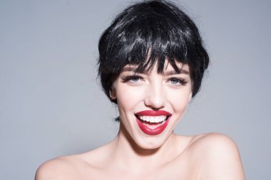 Dolgun dudaklar ve mükemmel cilt üzerinde gri arka plan izole kadın ile gülümseyen. Siyah kısa peruk, mutluluk ve sevinç kavramı kırmızı dudaklar ile güzel kız portresi