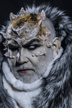 Siyah arka plan, cehennemdeki şeytanlar kapatın. Karanlık sanatlara kavramı. Beyaz sakallı komuta sizde canavar gibi giyinmiş. Dikenler veya siğiller kürk paltolu adam. Uzaylı, iblis, büyücü makyaj