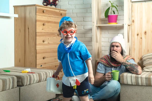 Сын в очках со стетоскопом и аптечкой позаботьтесь об отце на дому — стоковое фото