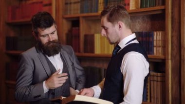 Erkek Profesör veya kitaplığındaki kitap bakarak öğretmenler portresi. Kitaplıkta arka plan ile kütüphanede iki bilim adamları tartışılması.