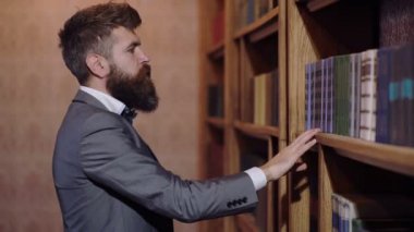 Seçim ve karar kavramı. Kitaplıkta seçim ayakta kılıyor. Bir adam bir kitap okuma için kitaplığa seçer..