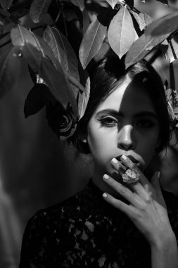 Bahar, yaz tatili. moda makyaj ağzına beyaz çiçek tutan kadınla