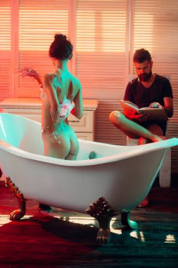 Çıplak kız yıkama iken WISP ile sakallı adam kitabını okudum. Seks oyunları arzu ve orgazm. İki aşık seksi vücut ile. Masaj ve aile spa kavramı. Çift banyo aşk ilişkileri köpük ile.