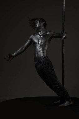 Güçlü dansçı egzersiz kutup. Özgürlük. Metal yüzey ile seksi maço. Pilon üzerinde dans gümüş gövde sanat kaslı adam. Pole dans spor. Atletik adam olun akrobatik öğeleri pilon üzerinde.