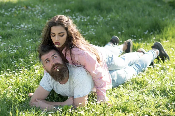 Çift aşk güneşli açık. Kadın adama ağız çiçeklerle yalan. Çift yeşil çimenlerin üzerinde rahatla. Kaygısız zaman birlikte. Yaz tatili keyfini