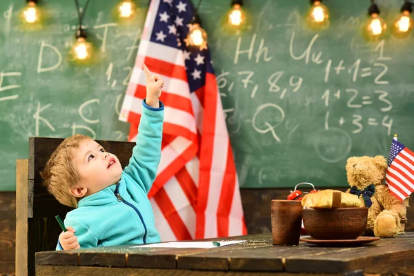 Lindo chico con bandera americana en pizarra en la escuela lección . —  Fotos de Stock