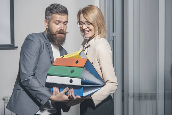 Romance de bureau et concept de flirt. L'homme aide la femme à porter des classeurs dans son bureau. Femme d'affaires et homme d'affaires avec des dossiers. Homme barbu et fille sexy avec des documents. Coopération entre entreprises et travail d'équipe — Photo