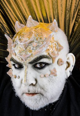 Dikenler veya siğiller, baş yüz pırıltılar ile kaplı, yakın çekim. Uzaylı, iblis büyücü makyaj. Sakallı canavar makyaj ile komuta sizde. İblis altın yaka, siyah arka plan ile. Fantezi kavramı.