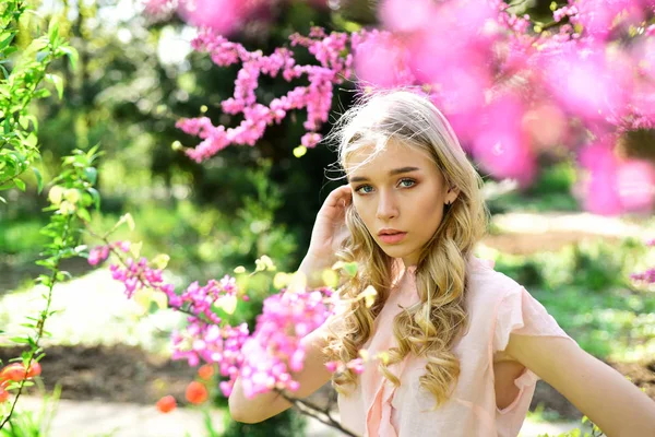 Lente bloei concept. Jonge vrouw genieten van bloemen in de tuin, intreepupil. Meisje op dromerige gezicht, tedere blonde in de buurt van violette bloemen van judas boom, natuur achtergrond. Lady wandelingen in het park op zonnige lentedag. — Stockfoto