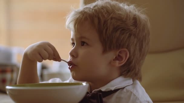 Babynahrung, Babynahrung. Kleiner Kerl genießt seinen Brei. Lustige Kinder essen Brei mit Milch. — Stockvideo