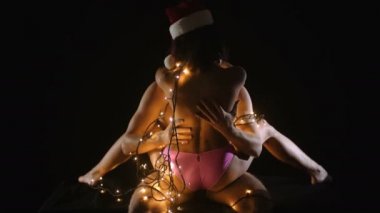 Kaç ışıklı çelenk içinde ilişkiler. Noel Baba adam ve kız çıplak vücut ile. Noel çift seksi erkek ve kadın aşık. Aşk ve seks oyunları.