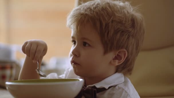 Мальчик наслаждается своей кашей. Забавный ребенок ест кашу с молоком. детское питание, детское питание — стоковое видео