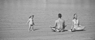 Aile yoga. Anne, baba ve çocuk kumsalda yoga egzersizleri yapıyor