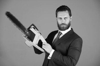 Fiyat kavramı kesmek. adam ya da ciddi sakallı işadamı tutun sarı chainsaw kıyafeti