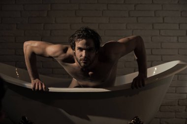 Küvet içinde oturan ıslak saçlı çocuk. Banyo kas vücut adamla.