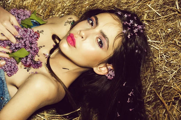 Kvinnligt mode koncept. ung kvinna med blomma på våren, sommaren på hö bakgrund — Stockfoto