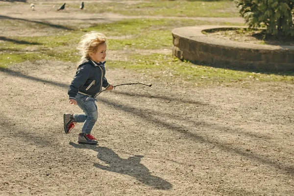 Concepto de Felicidad Infantil Infantil. Feliz niño en chaqueta azul y pantalones vaqueros con palo — Foto de Stock