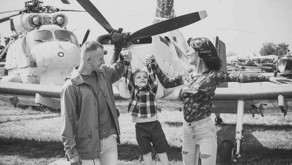 Familia en el museo de aviación. Familia feliz pasar tiempo juntos, en la excursión, helicóptero o avión en el fondo, día soleado. Madre y padre y su hijo caminando en el museo de aviación al aire libre —  Fotos de Stock