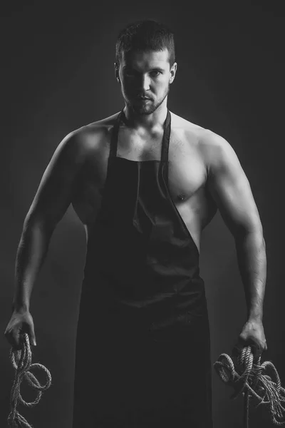 Brutal hard-boiled man. Muscular man in apron with rope — Stock Photo, Image