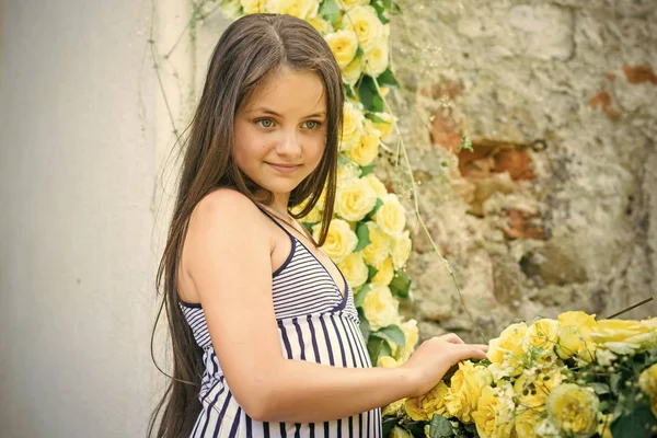Criança em uma feira de flores. Criança com rosas amarelas, primavera . — Fotografia de Stock
