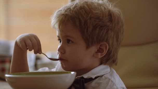 Ребенок концентрируется на просмотре мультфильмов и ест кашу — стоковое видео