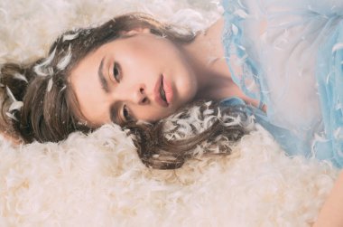 Güzel kız yumuşak yatakta boğulma. Tüylü beyaz tüyler, coziness kavramı dinlenme uykuya, Uykulu küçük hanım