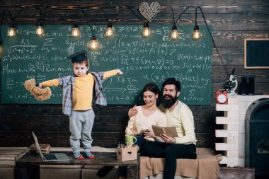 Destek kavramı. Çocuk oyuncak ayı ve gerçekleştirme tutar. Çocuk Anne ve baba için onun bilgi sunma. Oğulları, kara tahta arka plan dinleme anne. Lisansüstü şapkalı akıllı çocuk gibi gerçekleştirmek için