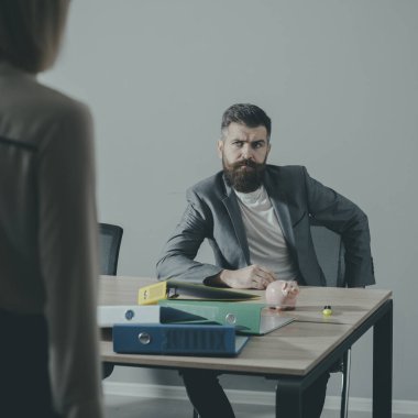 Ciddi patron ön planda bulanık kadın bak. Sakallı adam ofiste masada otur. Sakal ve bıyık resmi kıyafetli bir iş adamı. İş moda ve yaşam tarzı. İş süreci kavramı