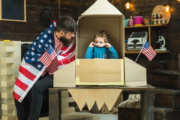 Feliz día de la independencia de los EE.UU. Padre y niño pequeño en un cohete de papel con bandera americana. Familia e infancia. Sueño con la carrera del cosmonauta. Patriotismo y libertad. Viajes y aventura —  Fotos de Stock