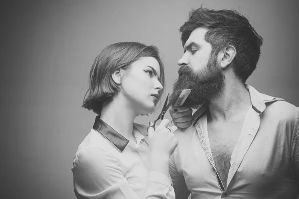 Barbería o concepto de peluquería. Mujer peluquera corta la barba con tijeras. Hombre con barba larga, bigote y pelo elegante, fondo claro. Chico con peinado moderno visitando peluquería . —  Fotos de Stock