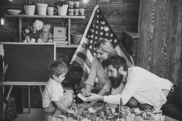 Amerikan aile ve sevimli oğlu ABD bayrakları ile oynamak. Oğlu Amerikan gelenekleri oynamak, öğretim veliler ebeveynlik tadını çıkarın. Anne ile çocuk plastik blokları bayraklarını ile oynamak. Vatansever eğitim kavramı.