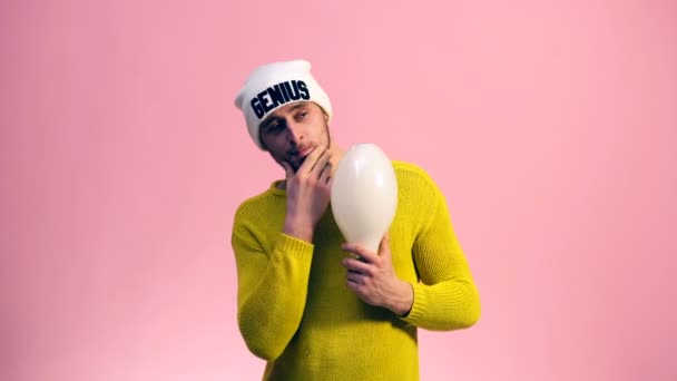 Il ragazzo con un maglione giallo con una lampada in mano pensa a una nuova idea. Lo studente pensa di migliorare la sua idea. Concetto di creazione di un'idea . — Video Stock