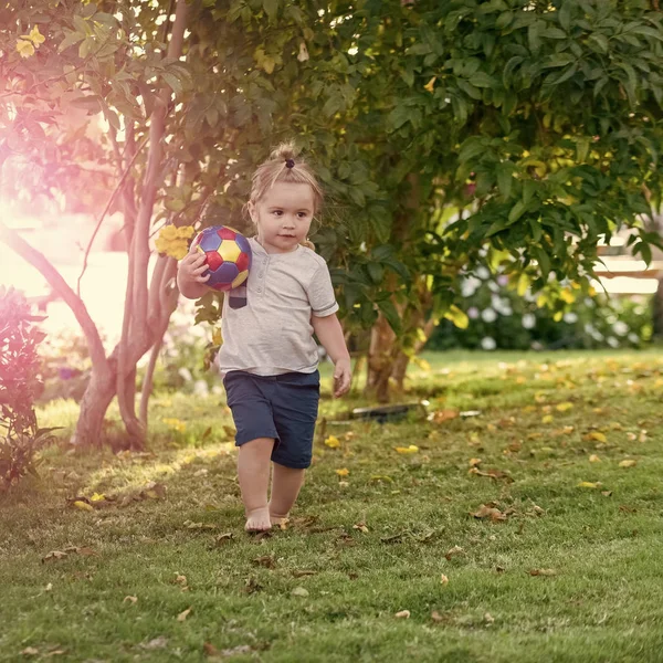 Dziecko gry z piłką na zielonej trawie na sielankowy dzień — Zdjęcie stockowe