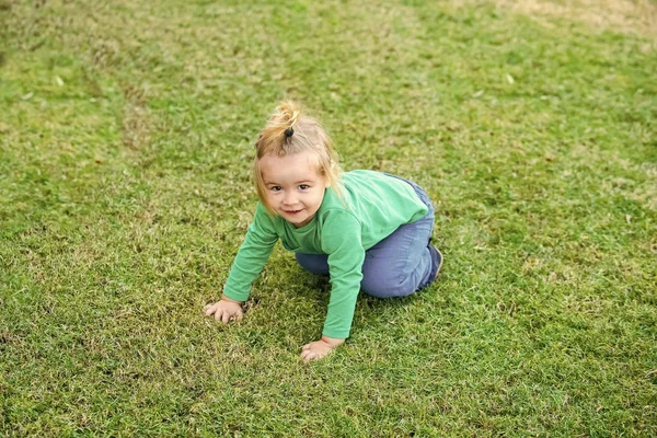 Niño está jugando en la hierba. Bebé niño sentado y divertirse en la hierba del prado —  Fotos de Stock