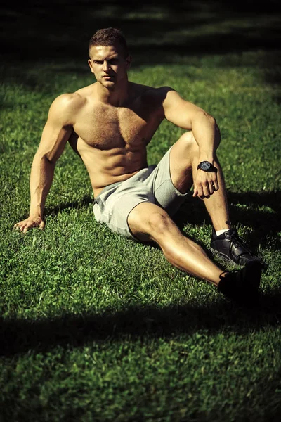 Yogalehrer. Mann Sportler mit muskulösem Körper sitzen auf grünem Gras — Stockfoto